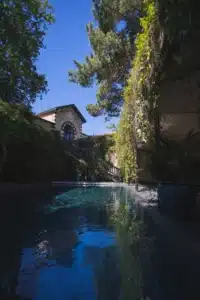 Piscine extérieure aux reflets bleus, encadrée de verdure luxuriante. Le bâtiment historique affiche «COMPAGNIE GENERALE DE SAUVETAGE».